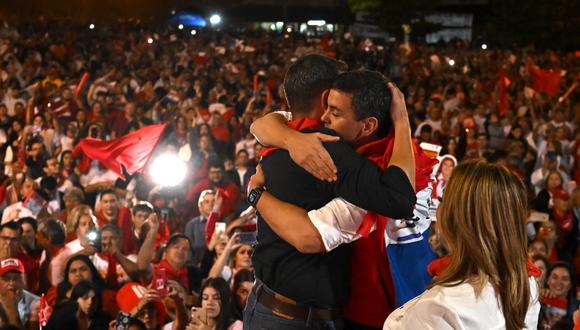 El candidato presidencial paraguayo por el Partido Colorado, Santiago Peña (R) abraza a su compañero de fórmula Pedro Alliana durante el mitin de cierre de su campaña en Asunción el 27 de abril de 2023. - Paraguay celebra elecciones generales y presidenciales el 30 de abril de 2023. ( Foto de Luis ROBAYO / AFP)