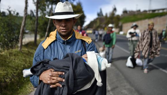 Richard Lomelly, de 30 años, lleva a su bebé Tiago, mientras camina por la carretera Panamericana, entre Pasto e Ipiales, Colombia, en su camino hacia el Perú. (AFP).