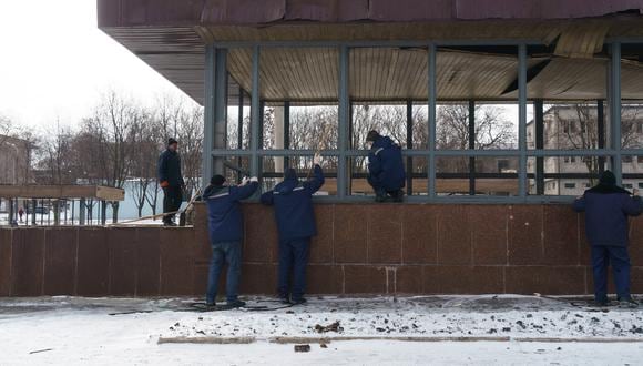 Trabajadores limpian los paneles de vidrio rotos del pabellón de entrada de una estación de metro luego de un ataque aéreo en Dnipro el 11 de marzo de 2022. (Foto referencial: Emre CAYLAK / AFP)