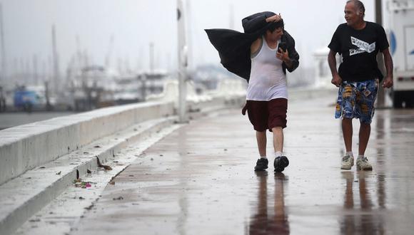 Dos personas soportan los fuertes vientos en Corpus Christi, Texas, antes de la llegada del huracán Harvey. (AFP)