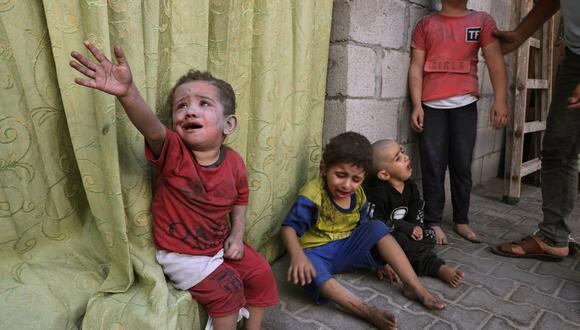Niños palestinos cubiertos de polvo por un ataque aéreo israelí se sientan en los terrenos de un hospital en Rafah, en el sur de la Franja de Gaza, el 23 de octubre de 2023, en medio de las batallas en curso entre Israel y el grupo palestino Hamás. (Foto de MOHAMMED ABED/AFP)