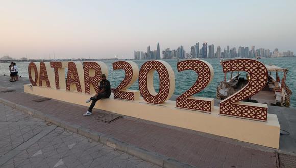 Un hombre se sienta en un cartel en Doha el 14 de noviembre de 2022, antes del torneo de fútbol de la Copa Mundial de Qatar 2022. (Foto de Giuseppe CACACE / AFP)