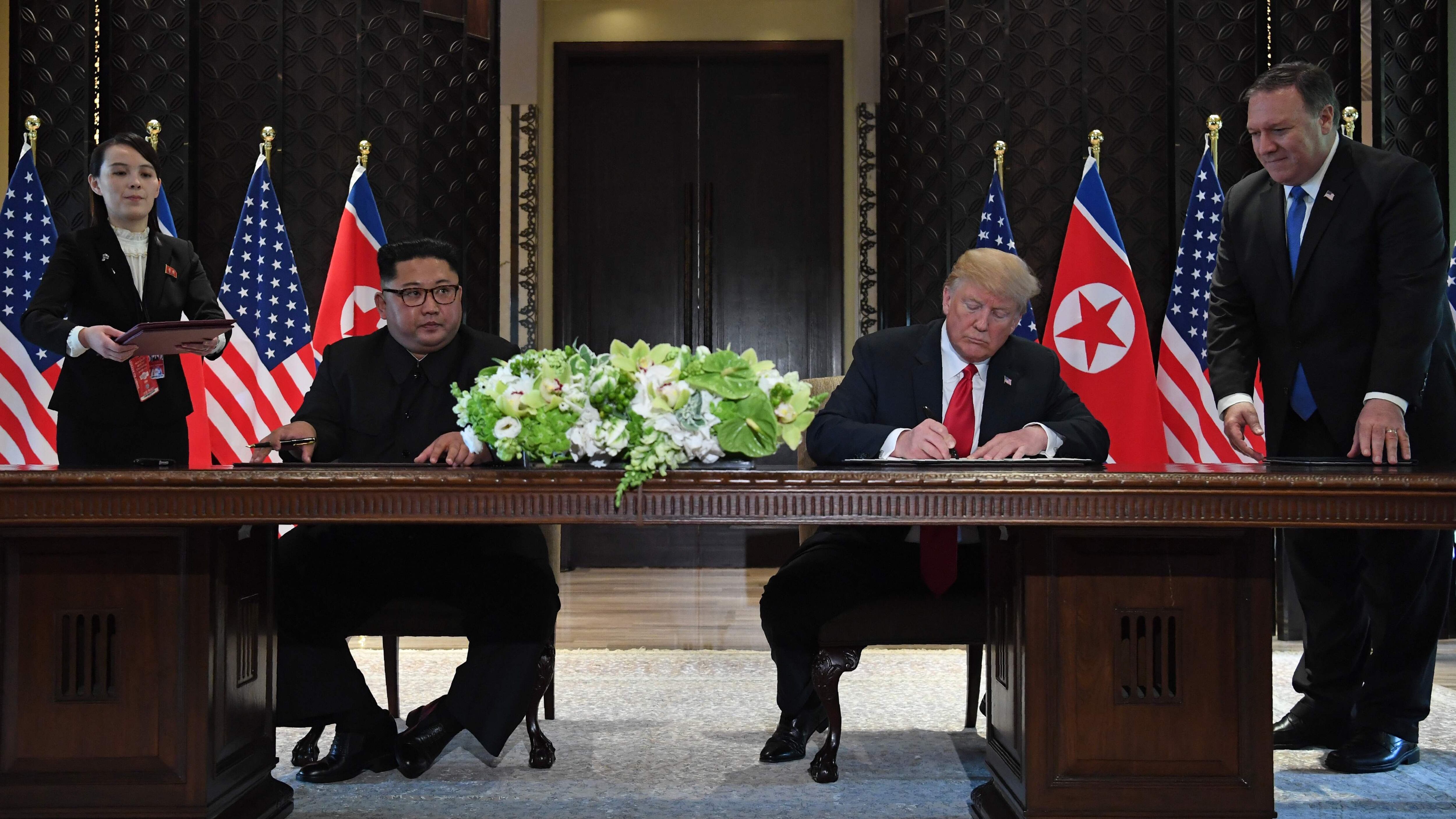 US President Donald Trump and North Korean leader Kim Jong-un sign documents as US Secretary of State Mike Pompeo (R) and North Korean leader Kim Yo's sister -jong, observe the ceremony during the historic summit between the two countries held in Singapore, on June 12, 2018. (Photo: AFP)
