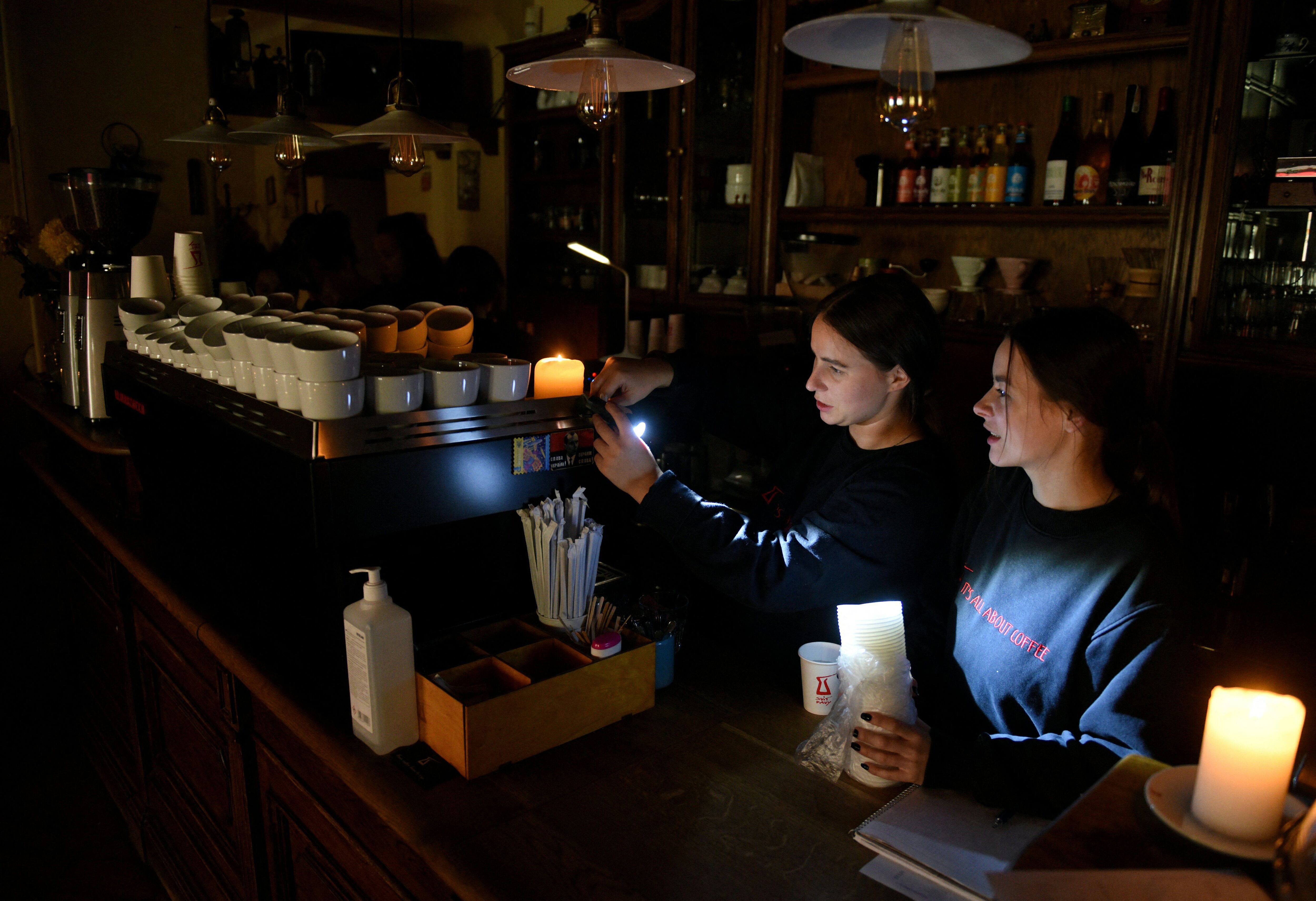 Employees prepare coffee at a cafe without electricity in the western Ukrainian city of Lviv after three Russian missiles fired at a power infrastructure on October 11, 2022. (Photo by Yuriy Dyachyshyn/AFP)