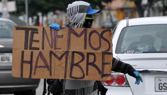 Un migrante venezolano sostiene un cartel que dice "Tenemos hambre" en las calles de Guayaquil, Ecuador, el 22 de abril de 2020, durante la pandemia del nuevo coronavirus, COVID-19. (Foto de José SÁNCHEZ / AFP)