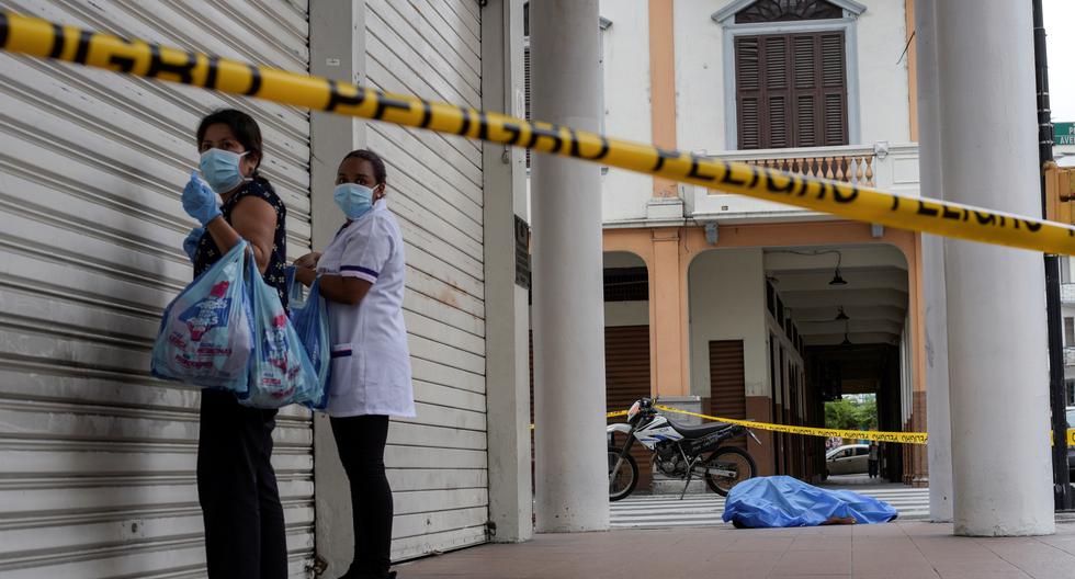 Una mujer parada junto al cadáver de un hombre que colapsó en la vereda durante el brote de coronavirus en la ciudad de Guayaquil, Ecuador. (Reuters)