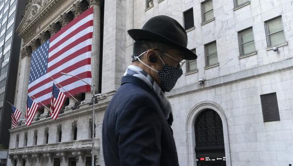 En esta foto referencial del 16 de noviembre de 2020, un hombre con una máscara pasa por la Bolsa de Valores de Nueva York en Nueva York.  (AP/Mark Lennihan).