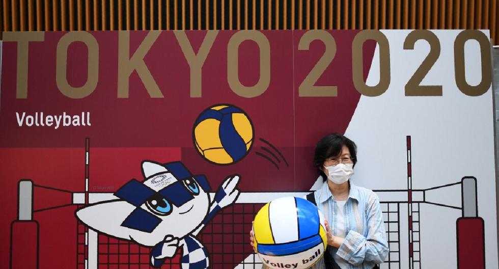 Una mujer usando una máscara posa frente a un tablero de Tokio 2020 durante el evento que marca la cuenta regresiva de un año antes del comienzo de los Juegos Olímpicos. (Archivo / AFP)
