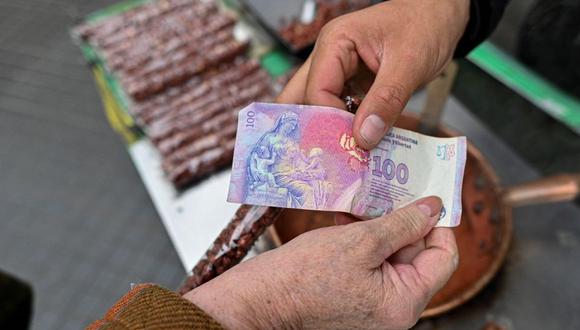 Imagen que muestra cómo dos mujeres intercambian un billete de 100 pesos argentinos. Las elecciones presidenciales en Argentina serán este domingo 22 de octubre | Foto: Agencias