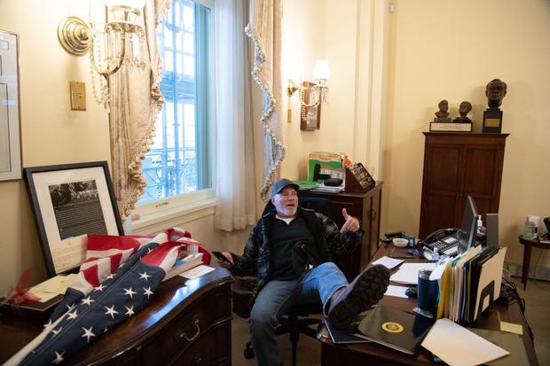 Richard Barnett, un partidario del presidente de Estados Unidos, Donald Trump, se sienta dentro de la oficina de la presidenta de la Cámara de Representantes, Nancy Pelosi, durante el asalto al Capitolio. (Foto de SAUL LOEB / AFP).