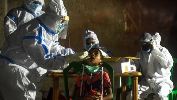 Un trabajador de salud realiza un hisopado a un niño de Calcuta, India, para determinar si tiene coronavirus COVID-19. (Foto: Dibyangshu SARKAR / AFP)