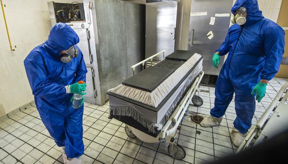 Trabajadores de una funeraria en México desinfectan el ataúd de una persona que falleció con COVID-19. (Foto: PEDRO PARDO / AFP)