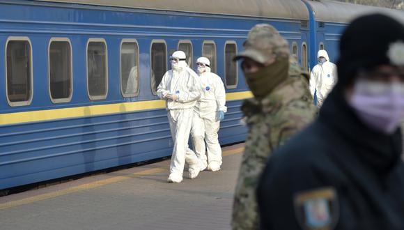 Trabajadores médicos caminan para revisar a los pasajeros de un tren con ucranianos evacuados de Moscú en la estación de trenes de Kiev, en medio de la propagación de la pandemia de COVID-19. (Foto: AFP)