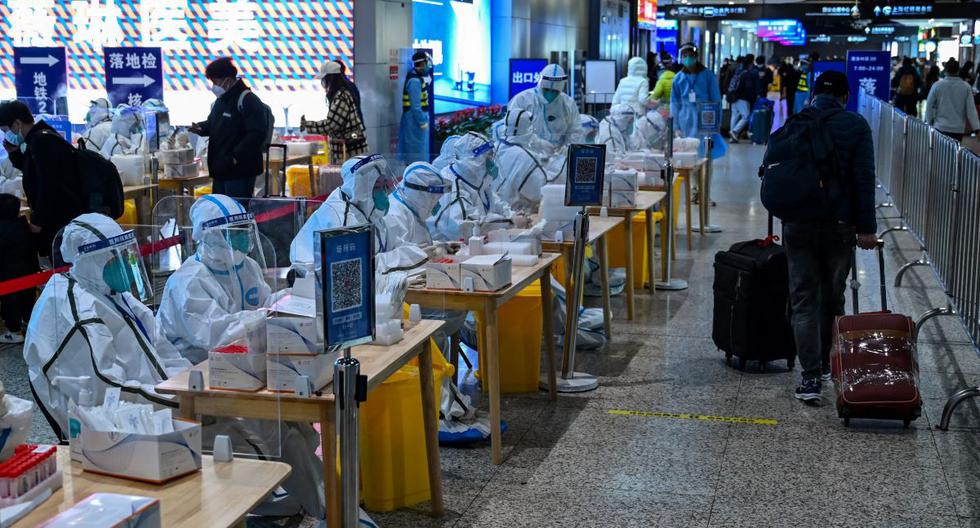 Trabajadores de la salud esperan para hacer pruebas de coronavirus covid-19 a los pasajeros después de su llegada a la estación de tren de Hongqiao en Shanghái, China, el 6 de diciembre de 2022. (HECTOR RETAMAL / AFP).