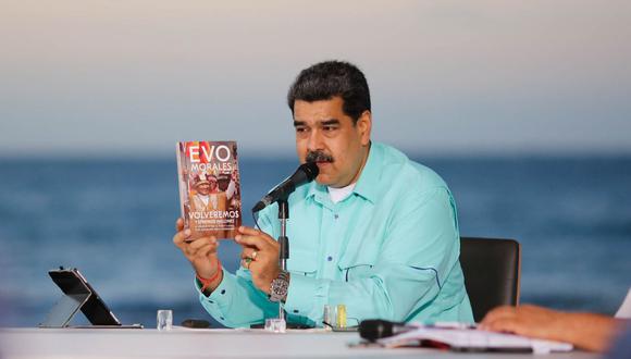 Nicolás Maduro muestra el libro que el expresidente boliviano Evo Morales le entregó durante su visita al país, durante un anuncio televisado en el estado de La Guaira, Caracas. (Foto: AFP/Venezuelan Presidency).