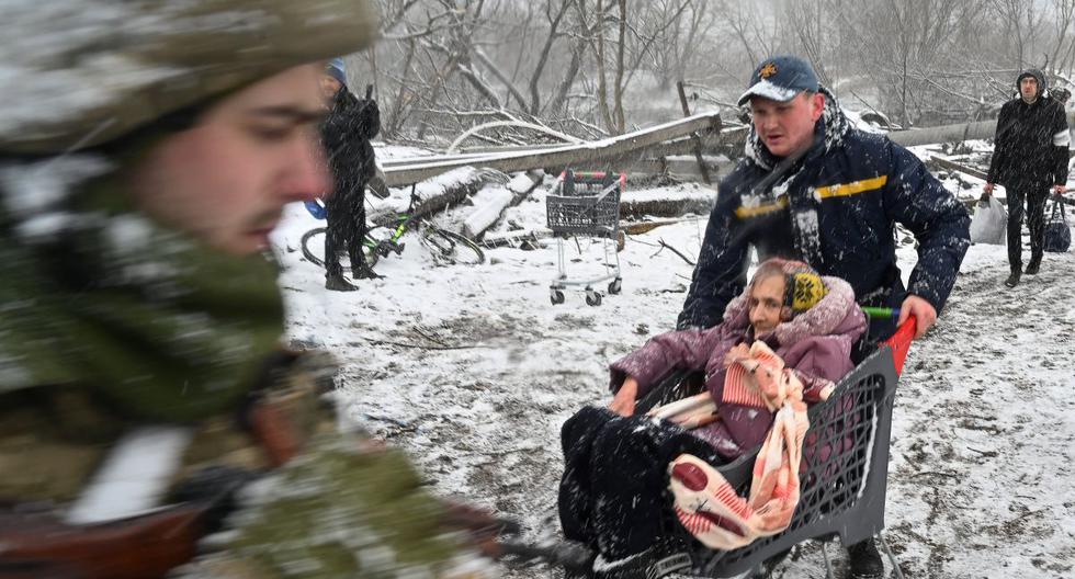 Un rescatista empuja un carrito donde va una anciana durante la evacuación de civiles de la ciudad de Irpin, al noroeste de Kiev, Ucrania, el 8 de marzo de 2022. (Sergei SUPINSKY / AFP).