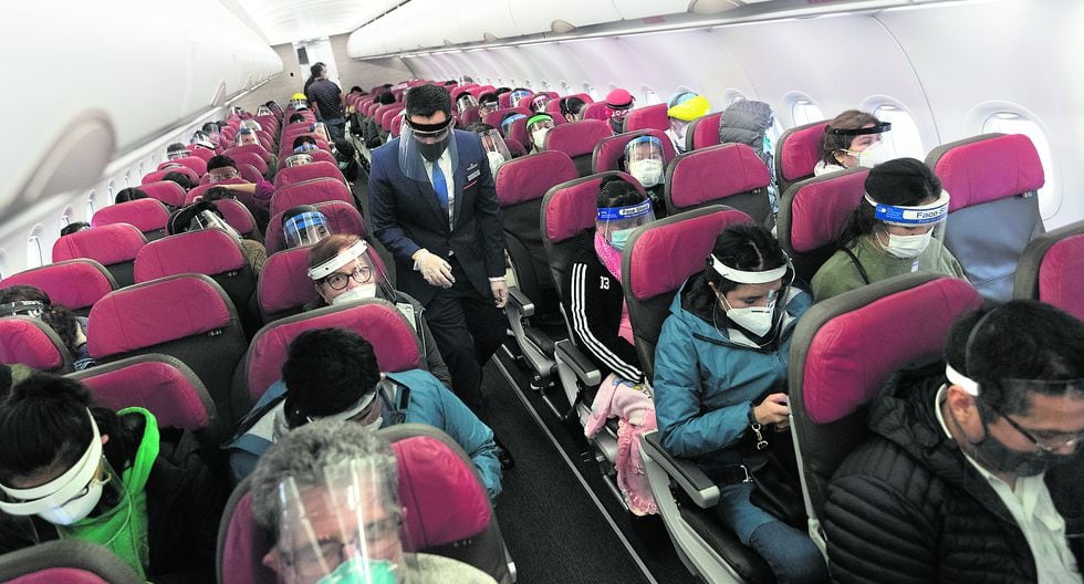 Los pasajeros del avión mantienen puestas sus mascarillas y caretas, previo a que el avión parta desde Lima con destino a Cusco. (Foto: Renzo Salazar)