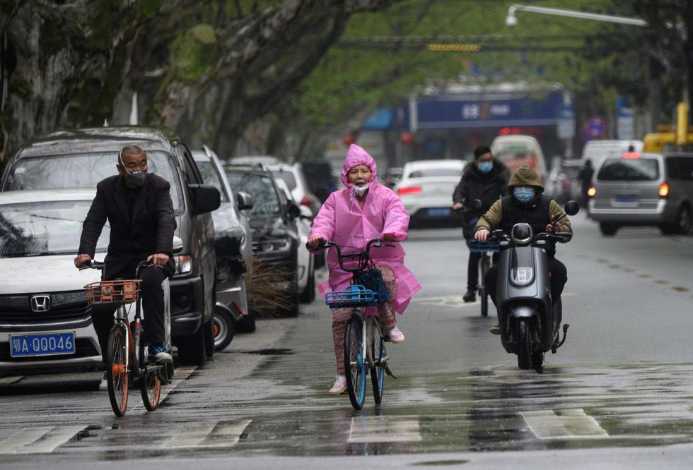 Las personas que usan máscaras viajan a lo largo de una calle en Wuhan, en la provincia central de Hubei de China. (Foto: AFP/Noel Celis)