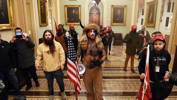 Partidarios de Donald Trump, incluido Jake Angeli, un partidario de QAnon conocido por su rostro pintado y su sombrero con cuernos, ingresan al Capitolio de los Estados Unidos el 6 de enero de 2021 en Washington, DC. (Foto de Saul LOEB / AFP)