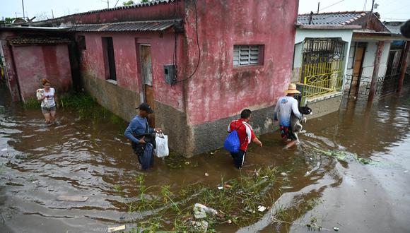 La gente camina por una calle inundada en Batabano, provincia de Mayabeque, Cuba. (Foto de Yamil LAGE / AFP)