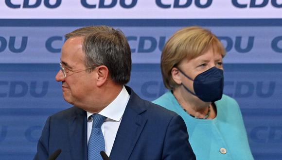 El líder de la Unión Demócrata Cristiana (CDU) y candidato a canciller Armin Laschet junto a la canciller alemana Angela Merkel llegan para dirigirse a la audiencia en la sede de la CDU después de las elecciones del domingo. (John MACDOUGALL / AFP).