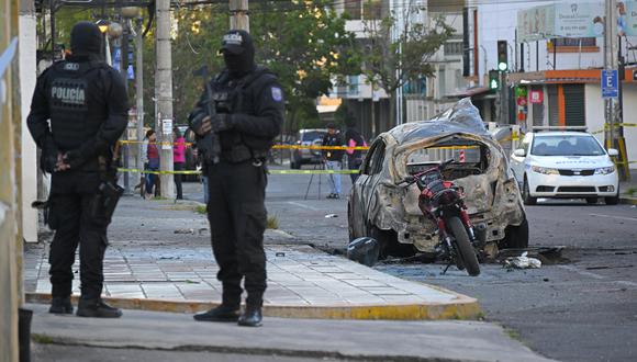 Los policías hacen guardia junto a los restos de un automóvil después de que explotó en Quito el 31 de agosto de 2023. (Foto: Rodrigo BUENDÍA / AFP)