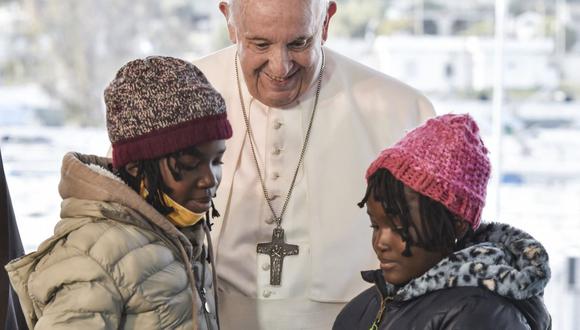El papa Francisco saluda a dos jóvenes refugiadas en el Centro de Recepción e Identificación (RIC) en la isla de Lesbos el 5 de diciembre de 2021. (Louisa GOULIAMAKI / AFP).