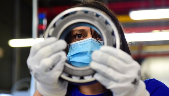Una trabajadora que usa máscara facial protectora labora en una fábrica de rodamientos metálicos para automóviles en San Benigno Canavese, Italia. (REUTERS / Massimo Pinca).