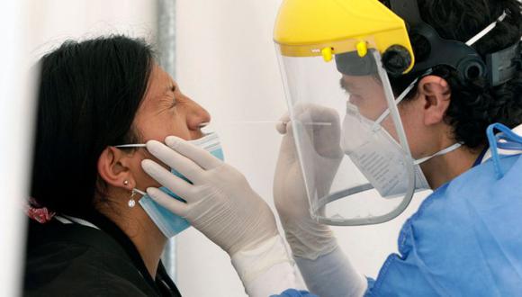 Un trabajador de salud toma una muestra nasal de COVID-19 de una mujer para una prueba de PCR en una carpa en el Hospital General IESS Quito Sur, en Quito. (Foto: Cristina Vega RHOR / AFP)