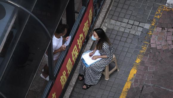 Una mujer habla con un hombre que está en cuarentena por coronavirus covid-19 en Shanghái, China, el 21 de mayo de 2022. (EFE/EPA/ALEX PLAVEVSKI).
