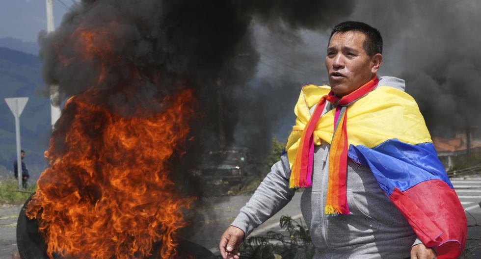 Un manifestante cubierto con una bandera ecuatoriana, protesta junto a una barricada en llamas durante una protesta contra el gobierno de Guillermo Lasso convocada principalmente por organizaciones indígenas, en Santa Rosa, Ecuador. (Foto: AP)