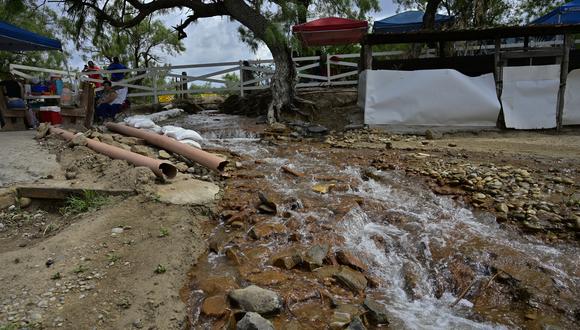 El agua que se extrae de la mina de carbón inundada donde 10 mineros han quedado atrapados desde el 3 de agosto, corre por la comunidad de Agujita, Municipio de Sabinas, Estado de Coahuila, México, el 14 de agosto de 2022.  (Foto de Pedro PARDO / AFP)