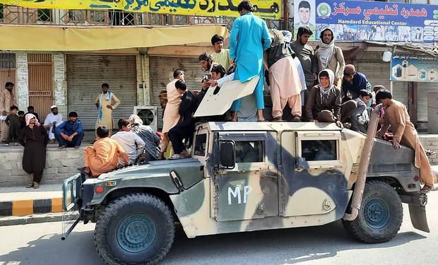 Taliban fighters and local residents sit in an Afghan National Army (ANA) Humvee vehicle in Laghman province on August 15, 2021.