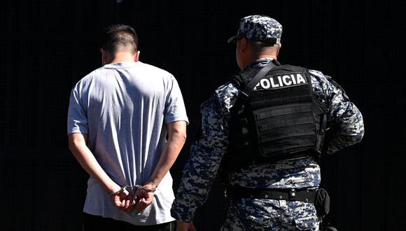 Un hombre arrestado por presuntos vínculos con pandillas es escoltado por un oficial de la Policía Nacional Civil durante el estado de emergencia declarado por el gobierno salvadoreño en el centro penitenciario de San Salvador, el 22 de junio de 2022 | Foto: MARVIN RECINOS / AFP