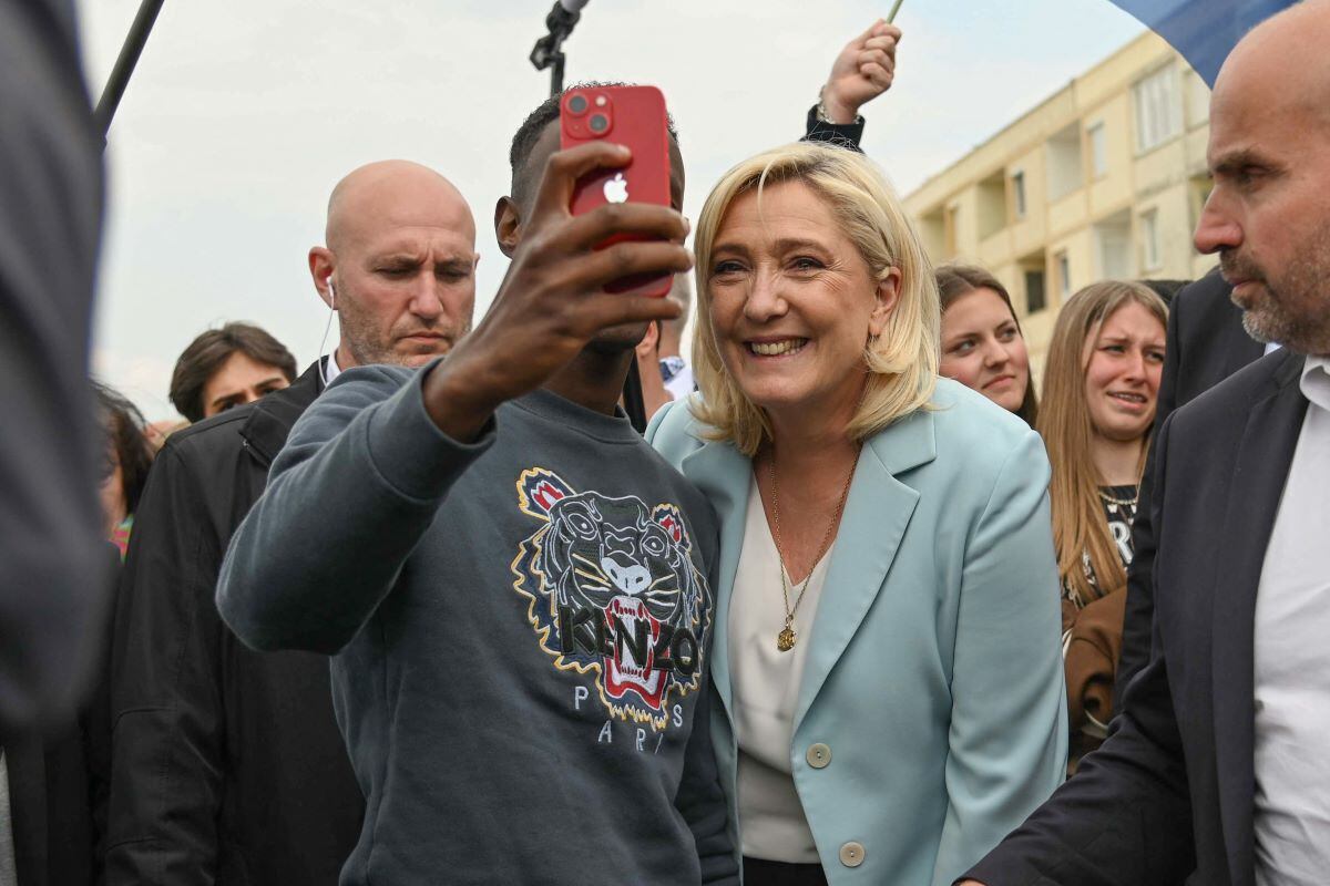 Marine Le Pen poses for a photo with a man during her visit to the coastal city of Berck on April 22, 2022. (Denis Charlet / AFP).