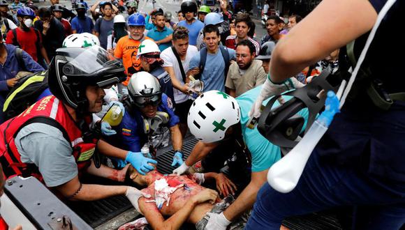 Neomar Lander es auxiliado en una camioneta luego de recibir el impacto de una bomba lacrimógena en el pecho. (Reuters).