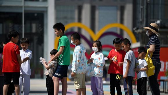 En esta foto de archivo tomada el 1 de junio de 2021, los niños hacen cola para su turno en un tobogán en el Día Internacional del Niño en Beijing, China. (NOEL CELIS / AFP).