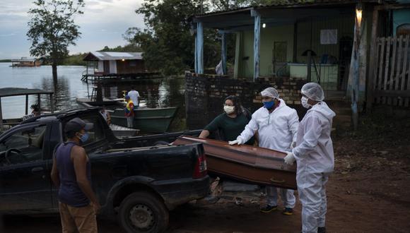 Trabajadores de SOS Funeral trasladan el féretro de una mujer de 86 años que vivía en Río Negro y se sospecha que murió de COVID-19, cerca de Manaos, Brasil, el 14 de mayo de 2020. El coronavirus se ha propagado río arriba hasta aldeas remotas y territorios indígenas donde para infectar a las tribus que viven allí. (AP Foto/Felipe Dana).