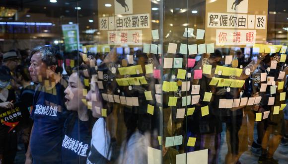 Los manifestantes en favor de la democracia cantan consignas mientras pegan carteles afuera de un centro comercial en apoyo del personal de Cathay Pacific en Hong Kong. (Foto: AFP)