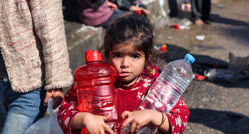 Una niña camina cargando botellas de plástico llenas de agua por una calle de Rafah, en el sur de la Franja de Gaza, el 8 de febrero de 2024, en medio del conflicto en curso entre Israel y el grupo militante palestino Hamás. (Foto de Mohammed ABED / AFP).