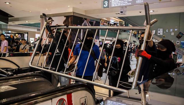 Los manifestantes traen elementos para formar una barricada que bloquea una entrada a la estación de MTR Sha Tin en el centro comercial New Town Plaza, Hong Kong. (Foto: AFP)