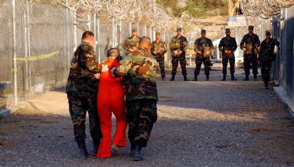 En esta foto publicada el 18 de enero de 2002 por el Departamento de Defensa, la policía militar del Ejército de Estados Unidos lleva a un detenido a su celda en el Campamento Rayos X en Guantánamo. (AFP PHOTO / US NAVY / Shane T.McCOY).