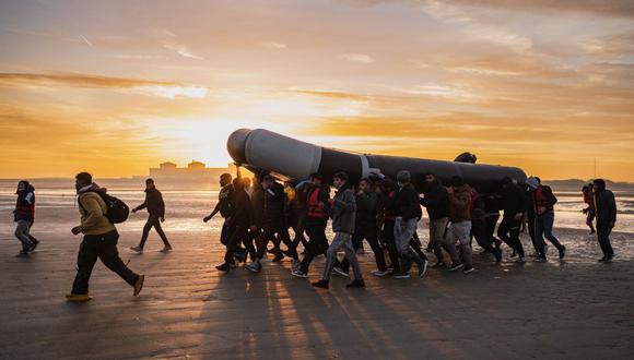 Los migrantes cargan un bote de contrabando sobre sus hombros mientras se preparan para embarcarse en la playa de Gravelines, cerca de Dunkerque, en el norte de Francia, el 12 de octubre de 2022, en un intento de cruzar el Canal de la Mancha. (Foto de Sameer Al-DOUMY / AFP)