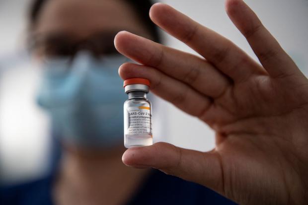 Chilean nurse María Paz Herreros, 32, who was the first to inoculate a patient against COVID-19 in Chile, shows a vial of the Chinese Sinovac vaccine.  (MARTIN BERNETTI / AFP).