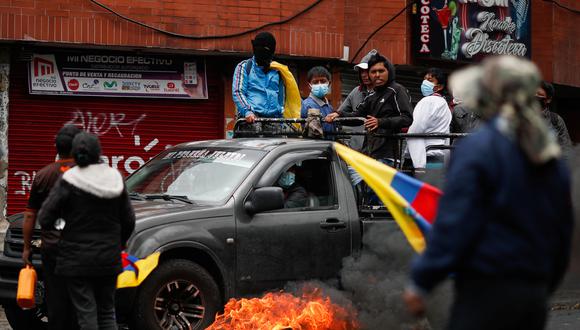 Manifestantes en un automóvil pasan junto a una llanta en llamas, mientras bloquean la calle durante una protesta antigubernamental en medio de un punto muerto entre el gobierno del presidente Guillermo Lasso en Quito, Ecuador.
