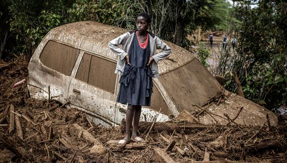 Una niña observa junto a un coche averiado enterrado en barro en una zona muy afectada por lluvias torrenciales e inundaciones repentinas en la aldea de Kamuchiri, cerca de Mai Mahiu, el 29 de abril de 2024. (Foto de LUIS TATO/AFP)