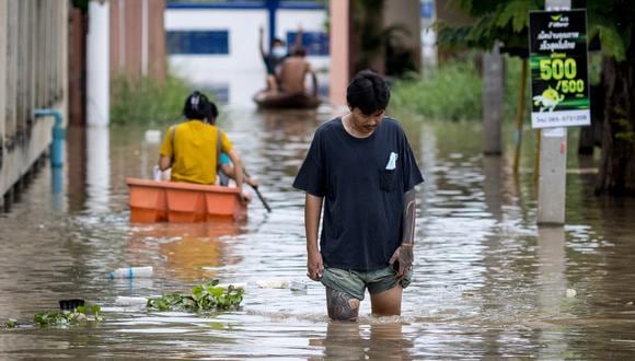 Un hombre sostiene sus pantalones cortos mientras camina a través de las inundaciones en un vecindario en Ayutthaya, en Tailandia, el 4 de octubre de 2021. (Foto: Jack TAYLOR / AFP)