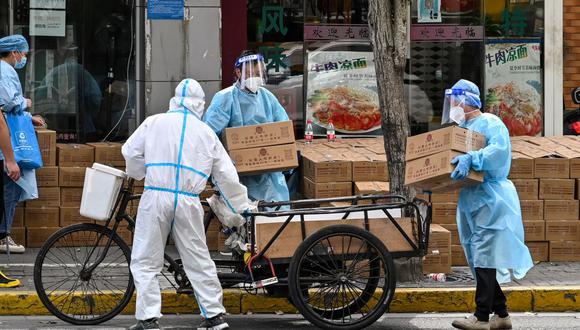 Los trabajadores que usan equipo de protección apilan cajas para entregar en un vecindario durante el confinamiento por coronavirus covid-19 en Shanghai, China, el 18 de mayo de 2022. (Héctor RETAMAL / AFP).