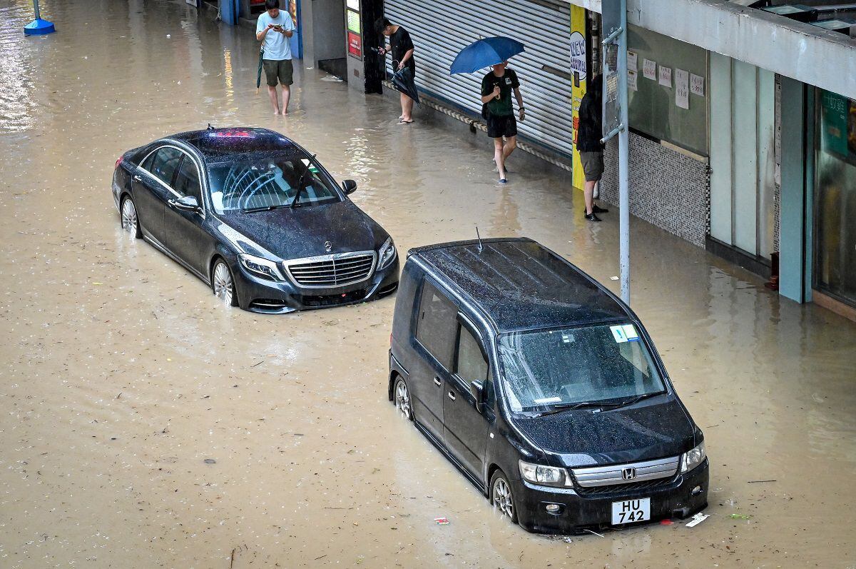 People walk through a flooded road in Hong Kong on September 8, 2023. (Photo by Mladen ANTONOV / AFP)