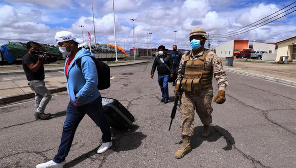 Un soldado chileno escolta a migrantes a las instalaciones policiales en Colchane, Chile, en la frontera con Bolivia, el 15 de febrero de 2022. (IGNACIO MUNOZ / AFP).